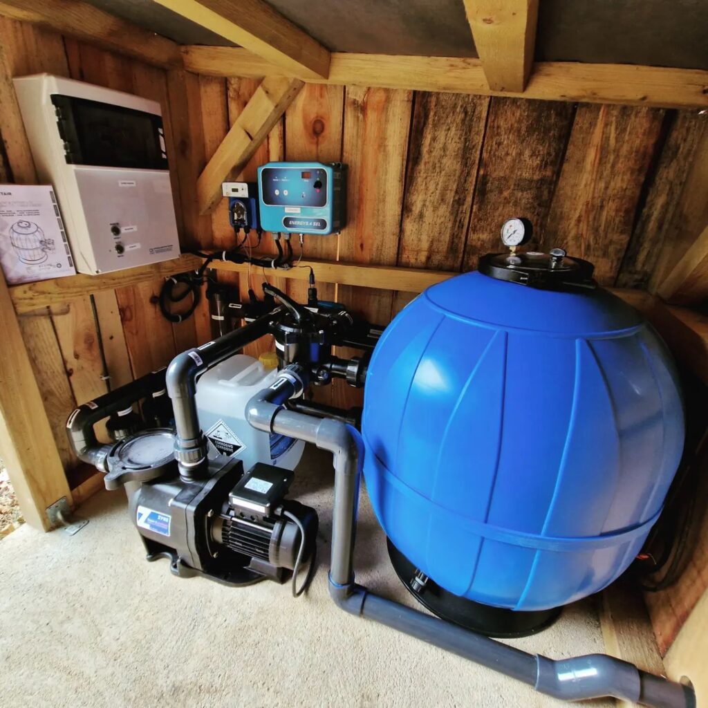 Local technique piscine en bois avec pompe Zodiac ZVMS, filtre bleu, panneaux de contrôle, dont Energy 4 Sel, et tuyauterie.